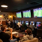 A dynamic scene of fans cheering while placing bets at keonhacaii88 during a live football match