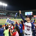 野球の試合で熱心に大谷翔平応援を祝うファンたち、歓声を上げる群衆で賑やかな雰囲気。