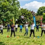 Acara Team Building jogja di taman luar ruangan yang cerah dengan kelompok yang terlibat dalam aktivitas menyenangkan.
