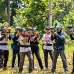 Exciting team building jogja paintball activity with diverse participants in lush forest.