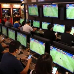Live sports betting atmosphere showcasing kèo nhà cái excitement with multiple screens and engaged bettors.